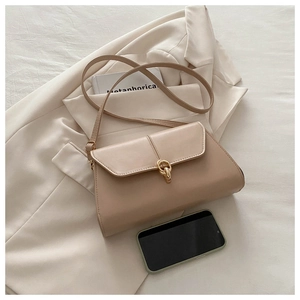 Détail du sac vintage beige avec fermoir en métal doré posé sur un blazer de couleur crème