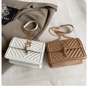 Close-up of white and camel V-quilted flap chain bags with metal logo and tassel details