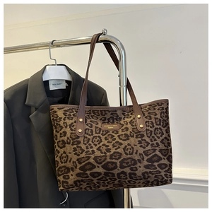 Close-up of leopard print tote bag with brown leather handles and gold brand logo plate