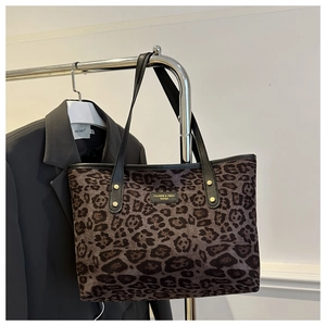 Detail view of large leopard print tote bag with black leather straps and metal rivets