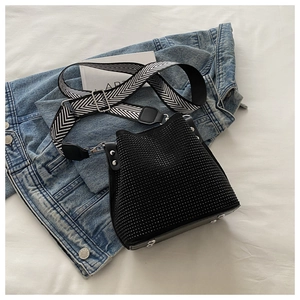 Détail du sac seau noir à strass avec texture cloutée et large bandoulière en toile tisse