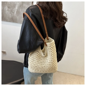 Detail of hand-woven cream tote bag with brown leather straps shown on shoulder