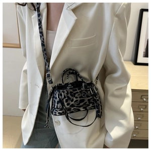 Close-up of leopard print mini crossbody bag styled with a white blazer and denim jeans