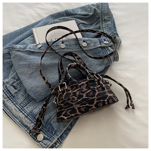 Detail of leopard print mini satchel with metal lock and drawstring on white surface