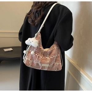 Detail of striped canvas tote bag with white leather strap and plush cloud charm accessory
