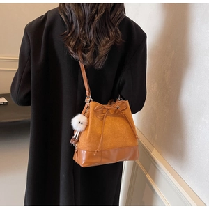 Detail of velvet and leather bucket bag with drawstrings and plush monster charm