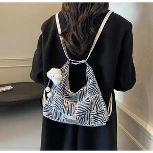 Detail of striped canvas tote with soft white cloud pendant shown on shoulder