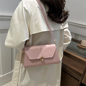 Sac à épaule chic en cuir rose avec boucle dorée porté sur un trench-coat beige