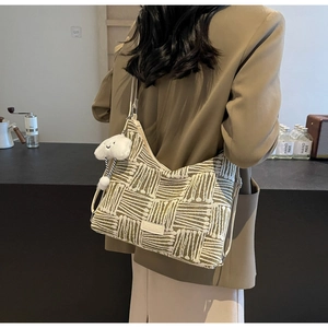 Detail of vintage striped knit tote bag with a plush cloud charm shown in lifestyle setting