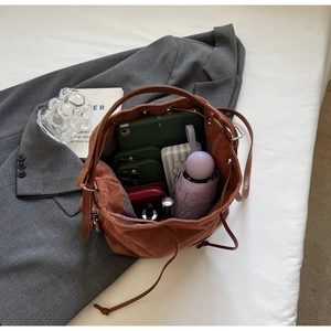 Interior storage detail of brown velvet bucket bag holding tablet, phone, and umbrella