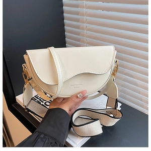 Detail of cream saddle bag with distinctive curved flap and dual strap options