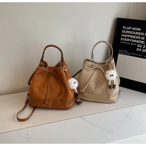 Detail of velvet bucket bags in brown and beige with cute white fur monster charms