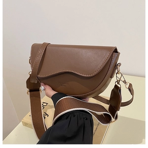 Detail view of brown PU leather saddle bag with wide canvas strap and gold hardware