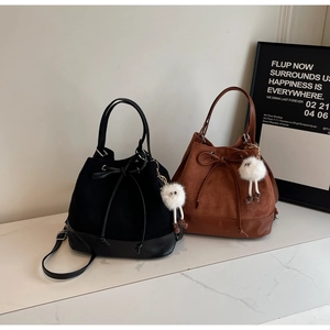 Detail of velvet drawstring bucket bags in black and brown with plush doll pendants