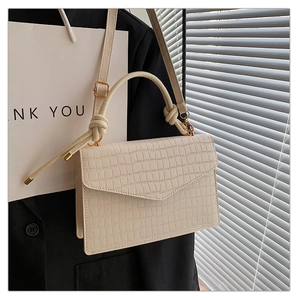 Detailansicht der cremeweißen Handtasche mit Krokoprägung und dekorativem Knotengriff