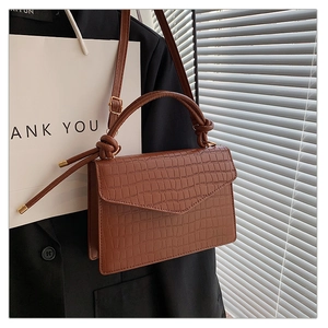 Detail der dunkelbraunen Kroko-Handtasche mit goldener Hardware und Tragegriff
