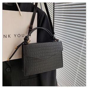 Detail der Krokoprägung und Knotengriff an der schwarzen Crossbody-Tasche