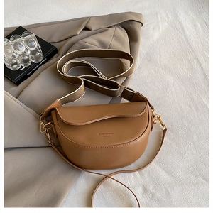 Detail view of brown faux leather saddle bag with two interchangeable shoulder straps