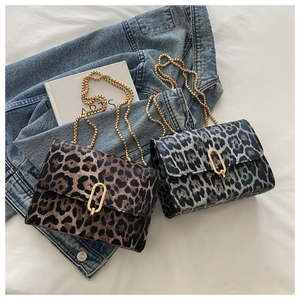 Detail view of stylish leopard print crossbody bags with elegant gold chain on a denim jacket
