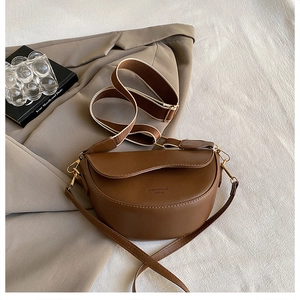 Detailed view of brown PU leather saddle bag with wide woven strap and gold hardware
