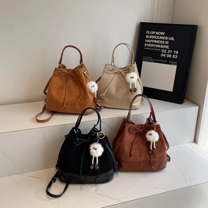 Minimalist drawstring bucket backpacks in suede and leather with plush monster charms
