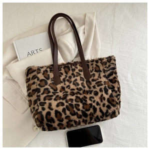 Macro detail of plush leopard print fabric and dark brown leather strap connection