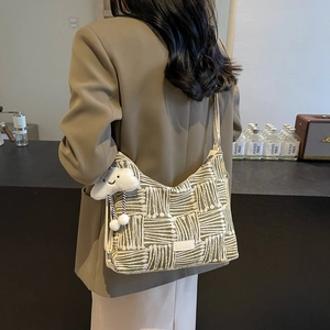 Green striped canvas tote bag with white plush pendant shown on a female model