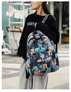 Street style view of a black graffiti print backpack with large front zipper pocket