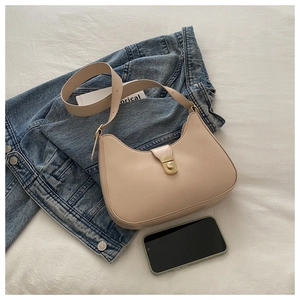 Detail of beige crescent underarm bag with gold twist lock on denim jacket background