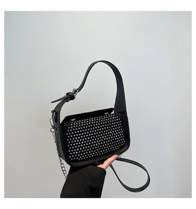 Detailed view of silver rivets on black leather handbag with metallic chain strap
