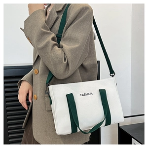 Borsa tote in tela con manici verdi mostrata a spalla in un ambiente d'ufficio informale