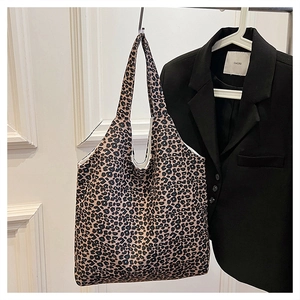 Detailed view of leopard print tote bag hanging on wall with stylish blazer background