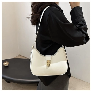 Detail of white hobo bag with a golden circular twist lock and minimalist shoulder strap