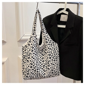 Detail view of a large canvas tote bag with black and white leopard print and wide shoulder strap