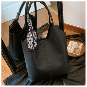 Detail of black pebbled leather tote bag with elegant blue silk scarf on the handle