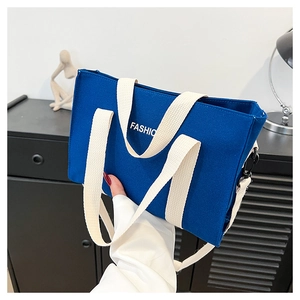 Dettaglio della borsa tote in tela blu scuro con scritta FASHIO bianca e manici in fettuccia