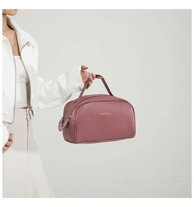 Detail of dusty rose PU leather cosmetic bag with gold logo and textured finish