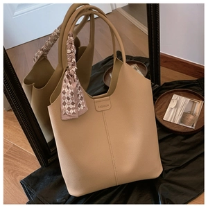 Detail of camel tote bag featuring lychee texture leather and elegant silk scarf handle