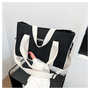 Dettaglio della trama in tela e del logo FASHION stampato su una borsa tote nera
