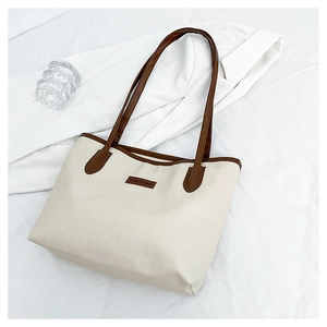 Detailed view of cream tote bag with brown straps and Fashion & Bags leather patch