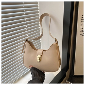 Detailed view of the golden swivel lock on a beige leather crescent underarm bag
