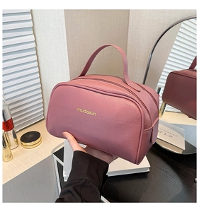 Close-up of pink PU leather makeup bag with litchi grain texture and double zipper