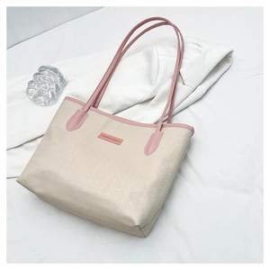 Detail of embossed PU leather tote bag with pink handles and fashion logo on beige surface