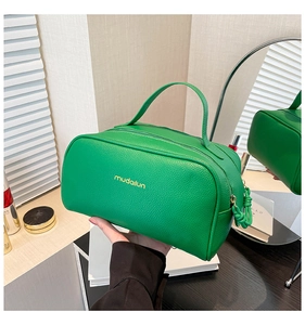Close-up of green PU leather toiletry bag with lychee texture and gold logo detail