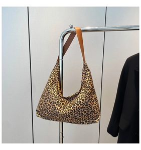 Dettaglio della borsa tote leopardata in tela con robusti manici in pelle marrone scuro