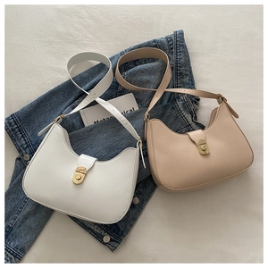 Detail of white and beige crescent shoulder bags with gold twist locks on white fabric