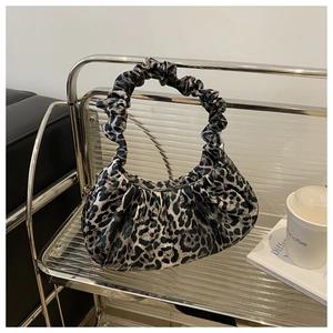 Detail of trendy leopard print handbag with ruched handle in a modern urban setting