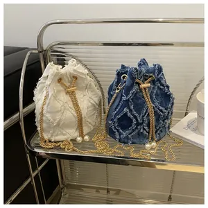 Close-up of denim bucket bag with frayed quilted patterns and pearl drawstring details