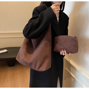 Close-up of brown suede tote bag set with matching small zipper pouch worn by a model