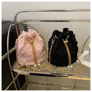 Close-up of quilted denim bucket bags with gold chain straps and pearl drawstring tassels